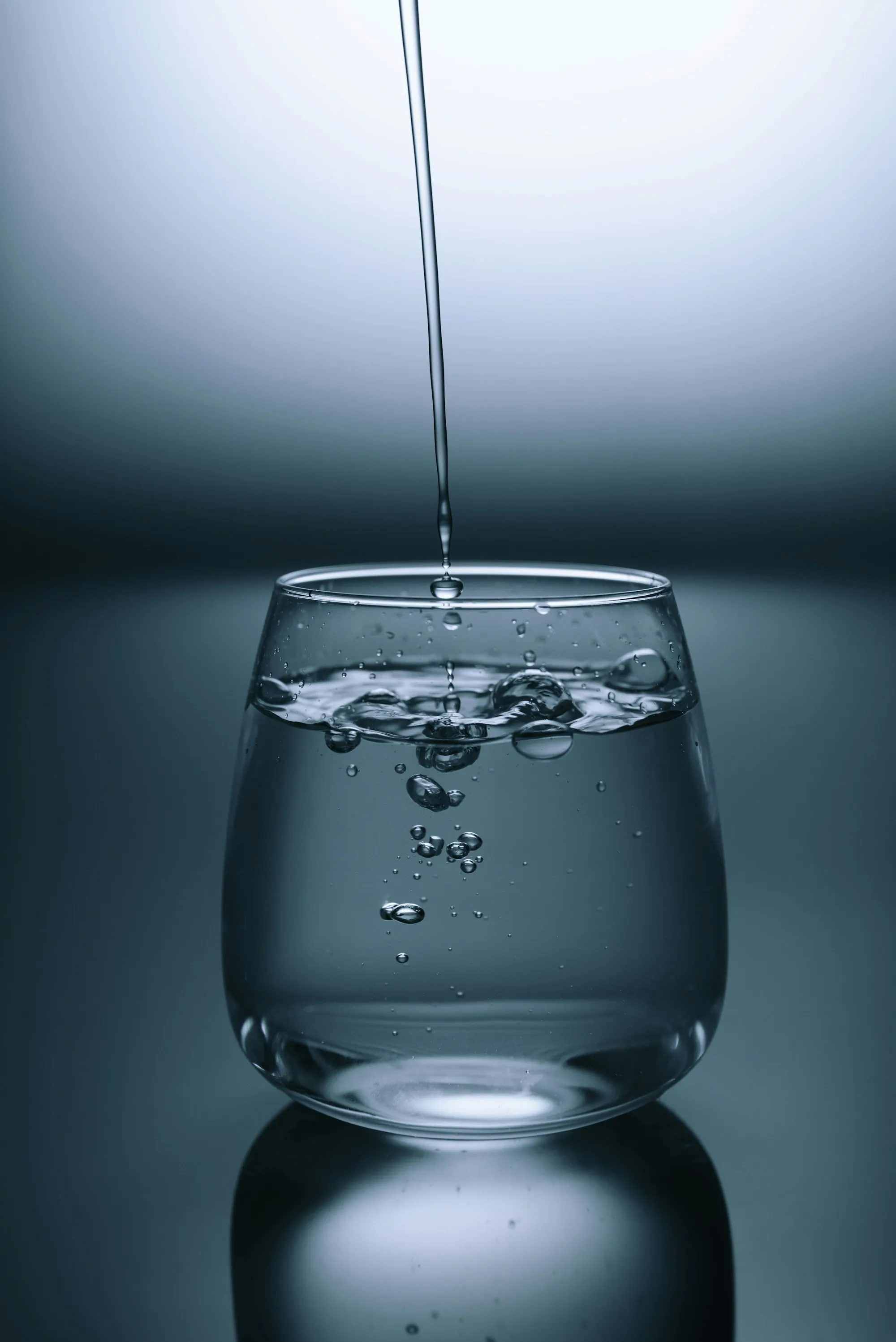 A glass of water with small bubbles against a soft blue background