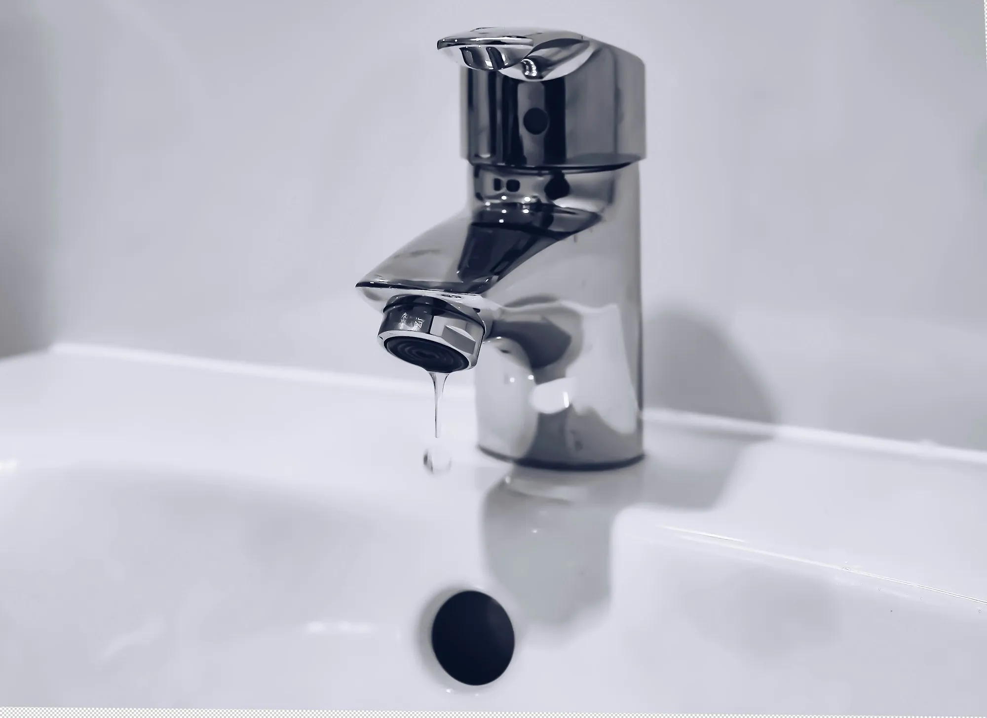 A chrome faucet with water running into a white basin