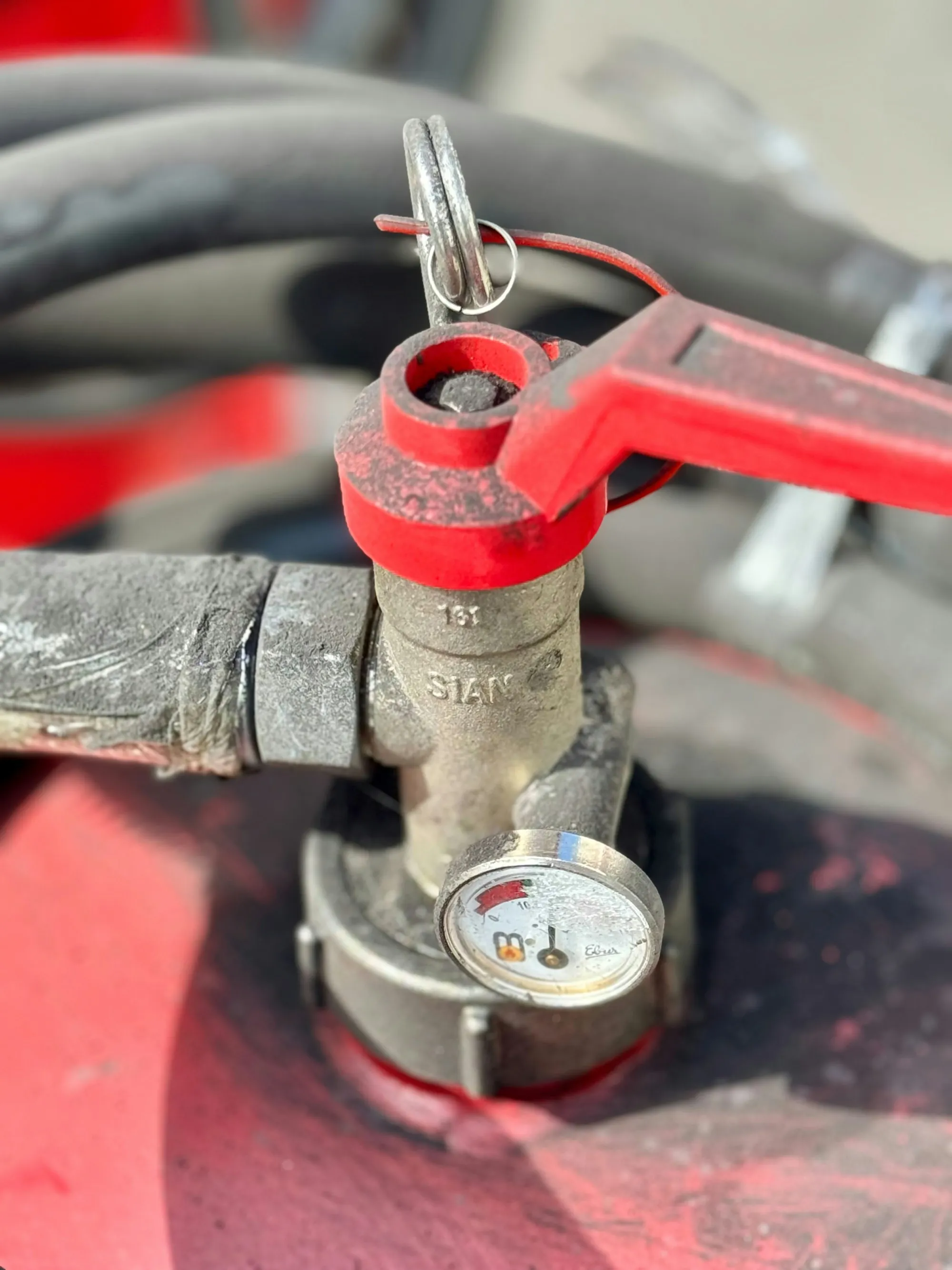 A red-handled shut-off valve on a household supply line