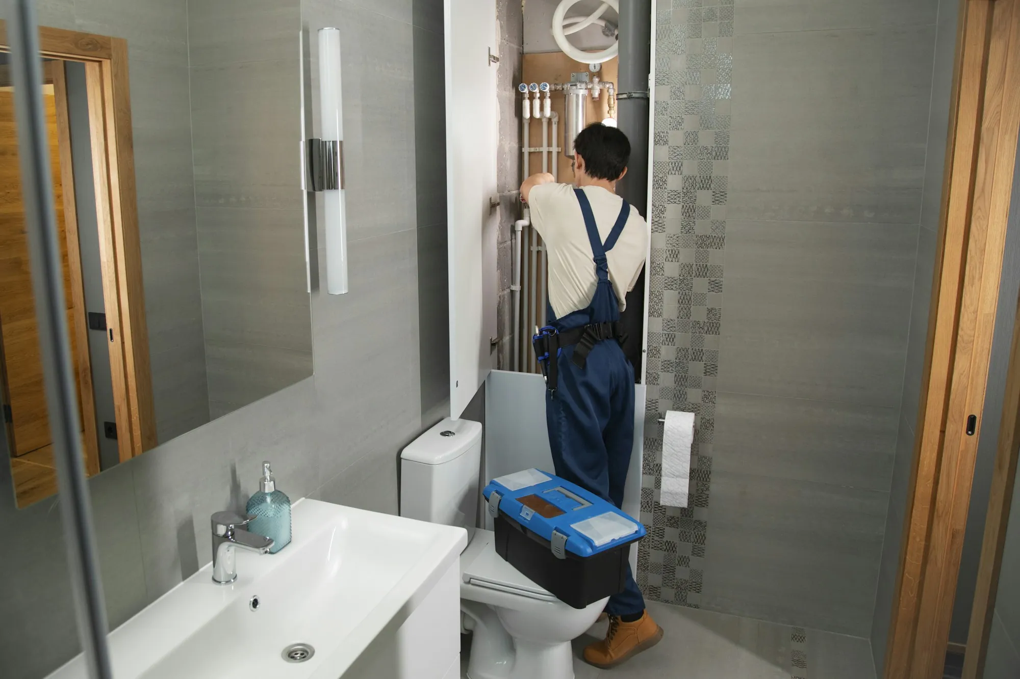 An installer checking fittings in a bright, modern bathroom