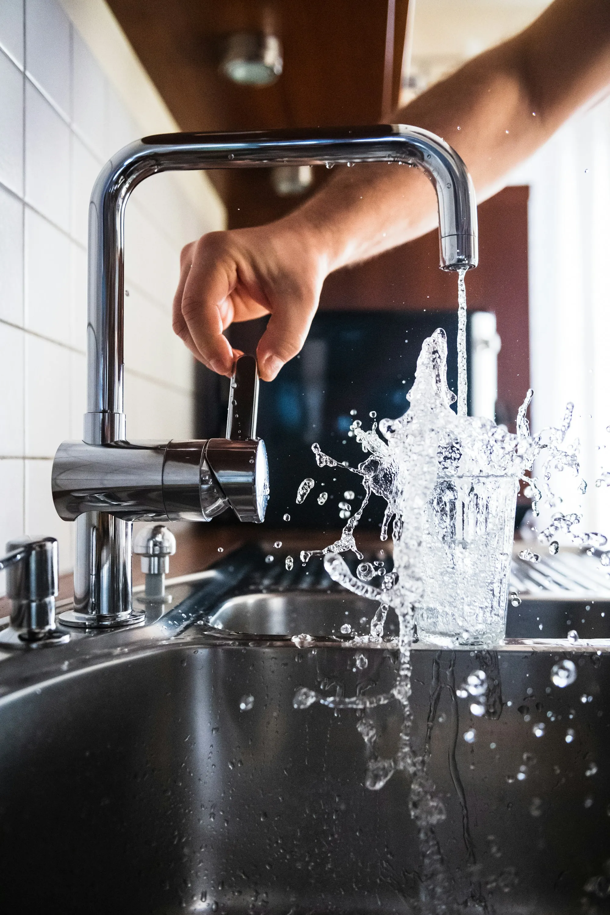 Water splashing from a kitchen faucet into a glass