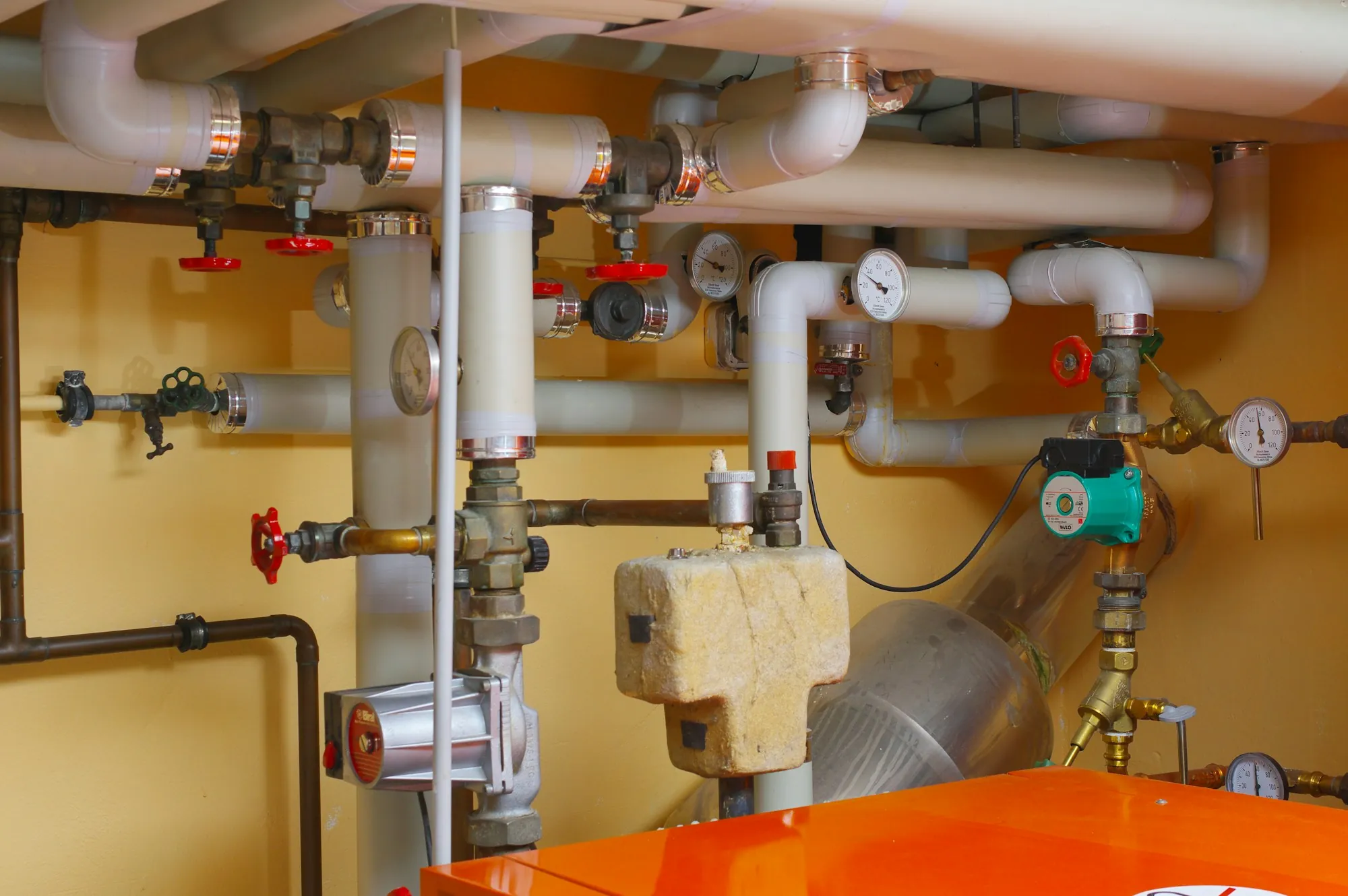A tidy manifold of supply pipes, valves and gauges on a utility wall