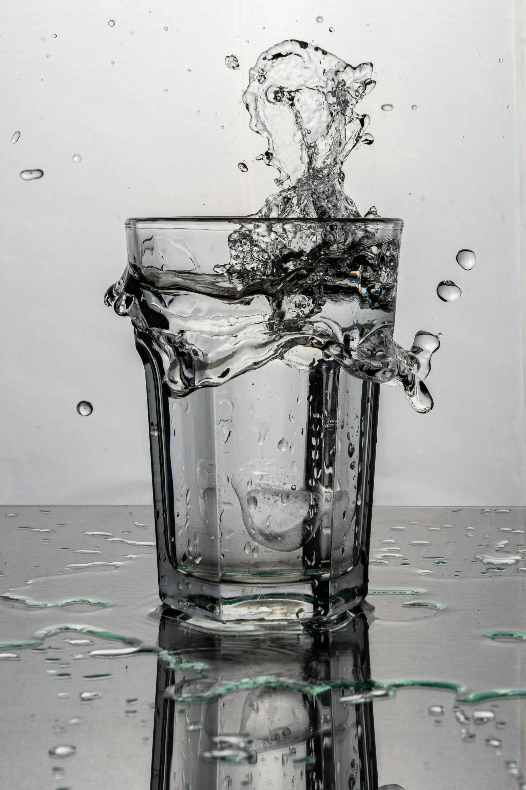 Water pouring into a clear glass against a light background