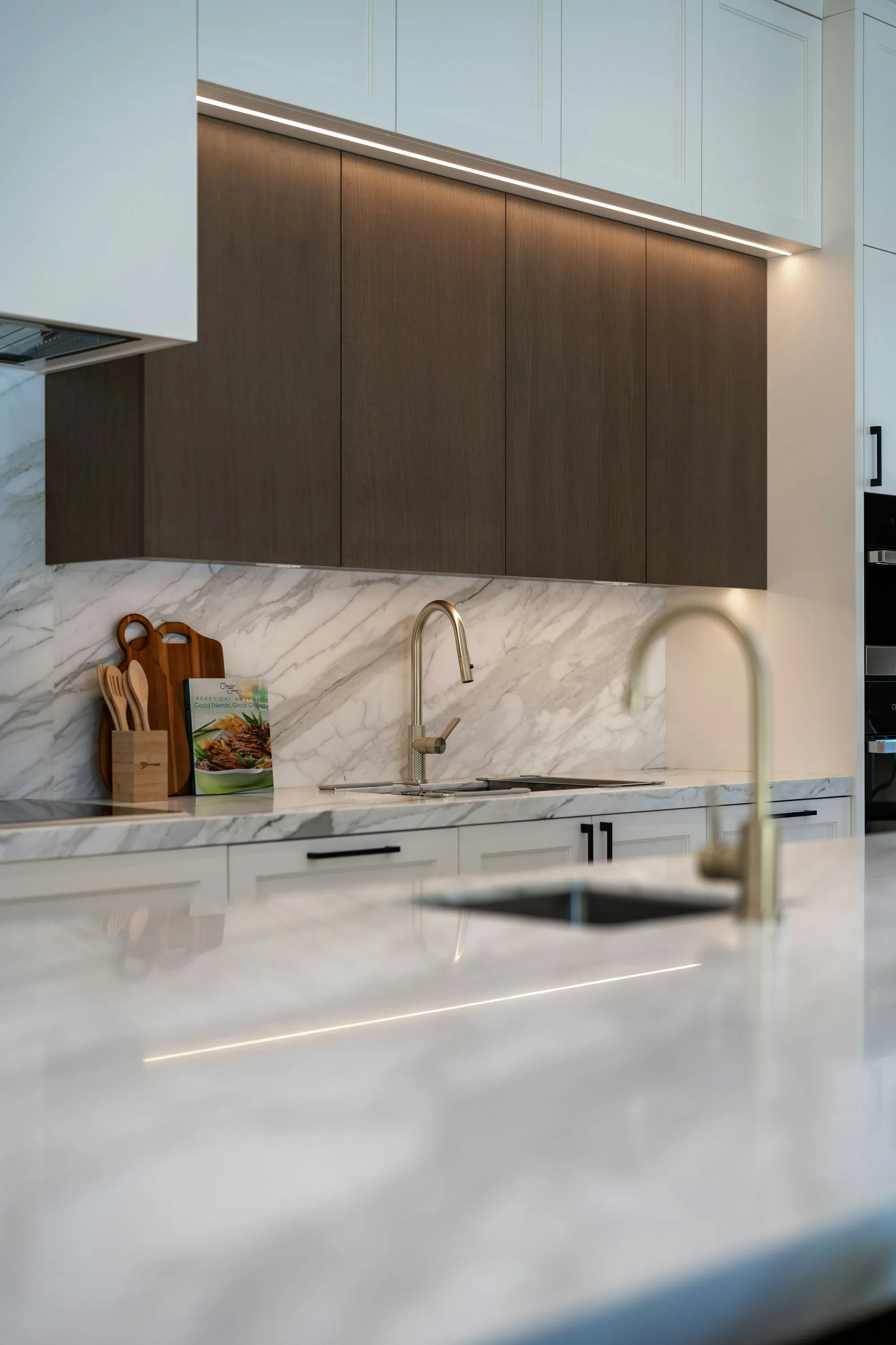 A modern kitchen with a gooseneck faucet over a stone countertop