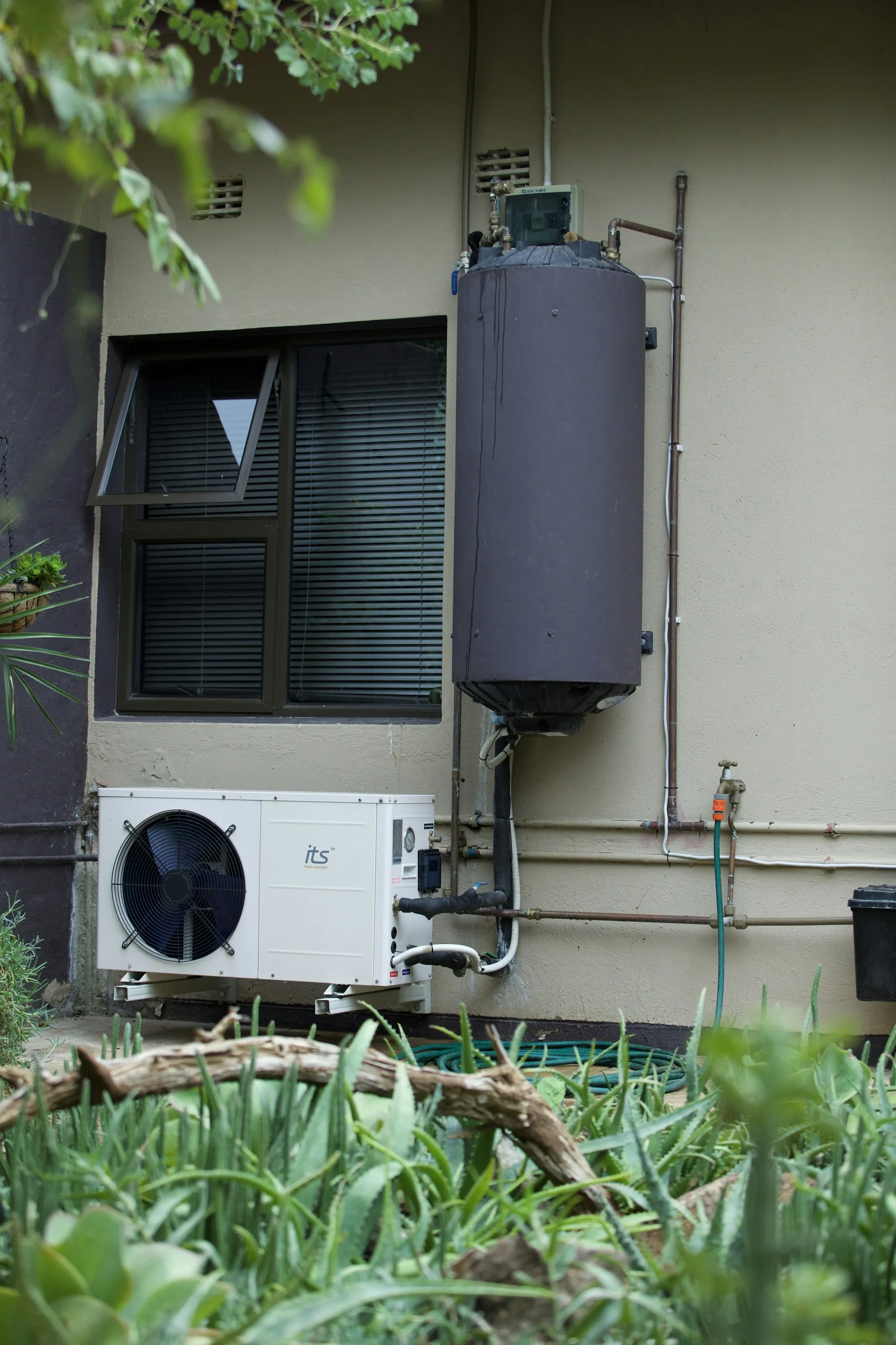 A wall-mounted water heater and plumbing in a home utility space