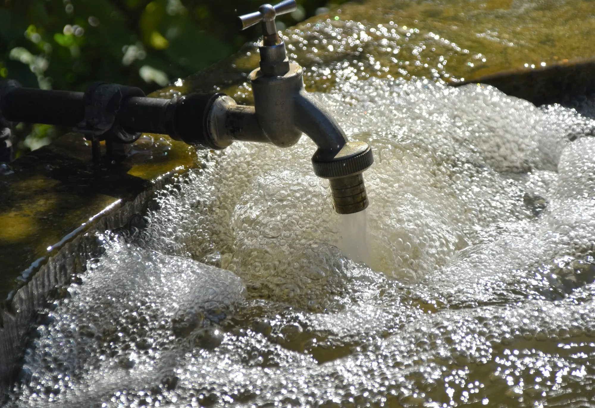 Water bubbling over white foam beneath an outdoor spigot